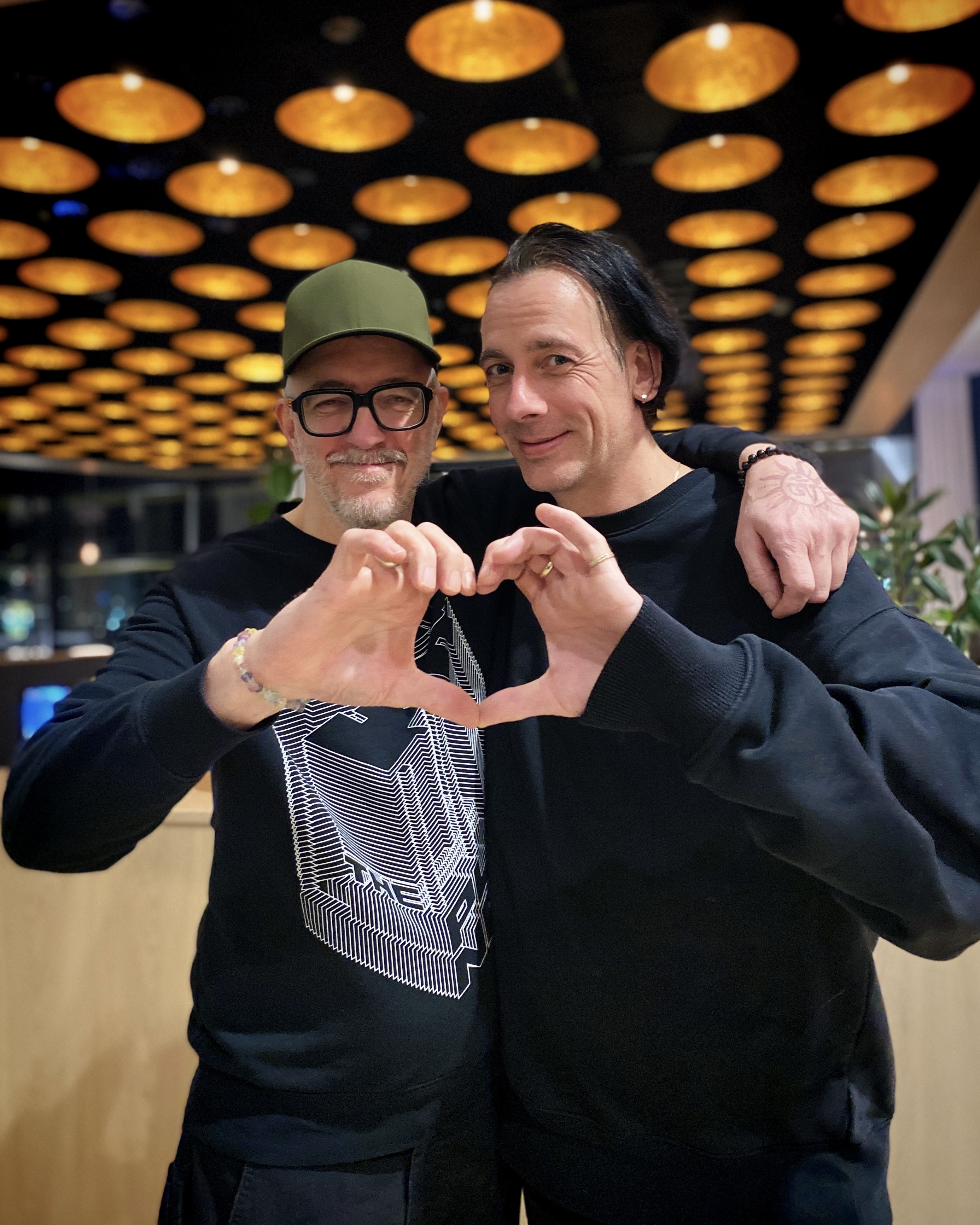 Dr. Motte (right) and Martc van Linden (left) form a heart with their hands.