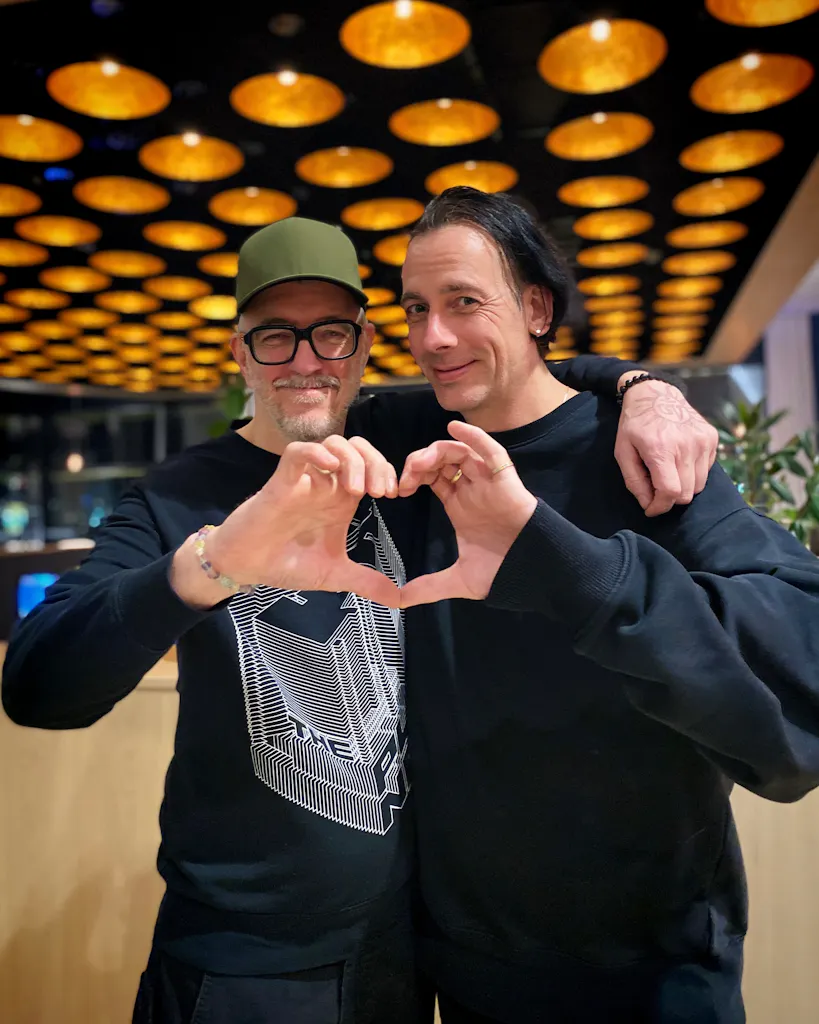 Dr. Motte (right) and Martc van Linden (left) form a heart with their hands.