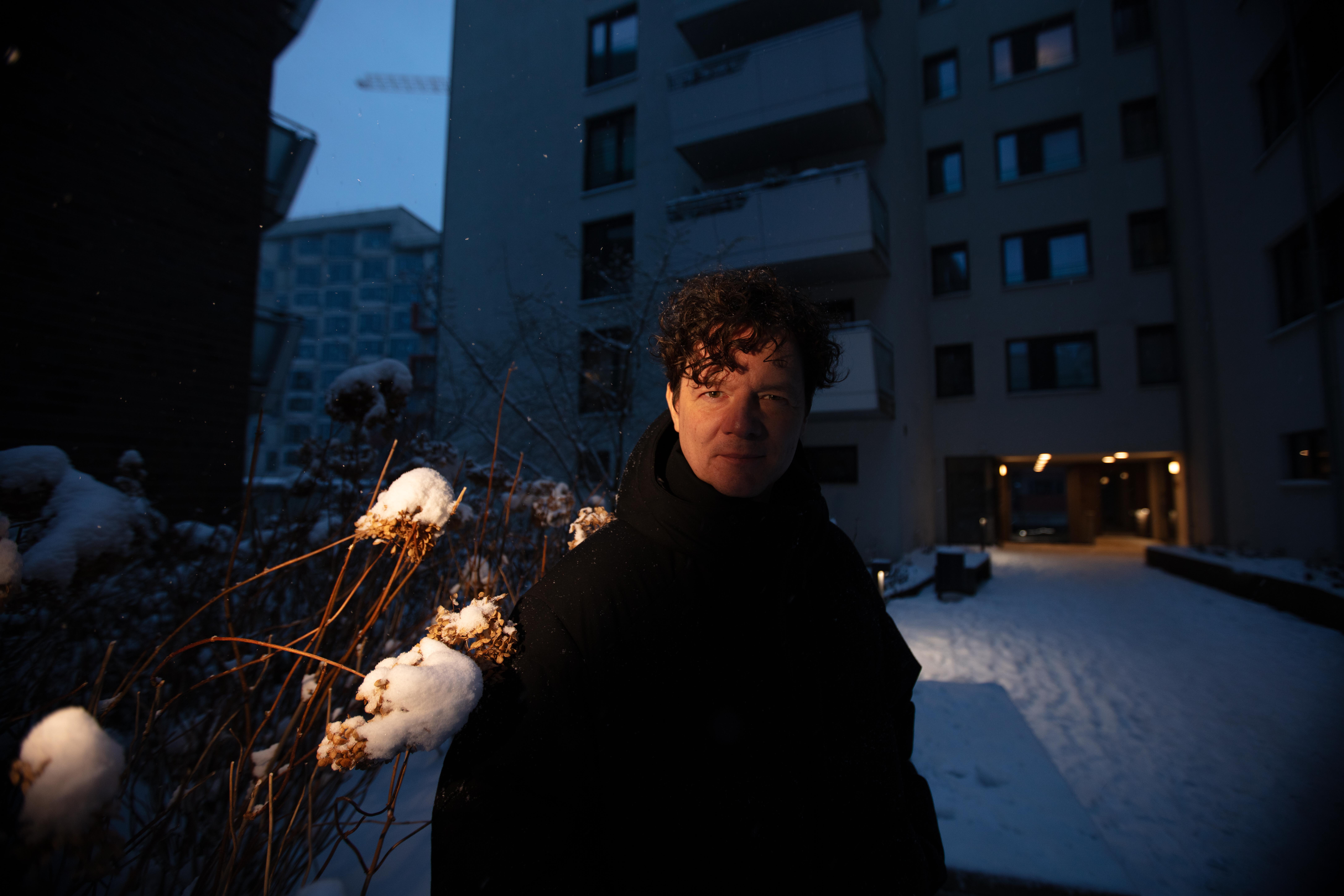 André Winter steht in einem tief verschneiten Hof einer Wohnblocksiedlung